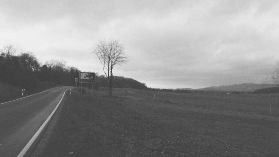 Blick entlang der Landstraße, die die Landkreise Nordhausen und Göttingen verbindet. Am Straßenrand ein Schild, das zeigt, dass Deutschland und Europa an dieser Stelle getrennt waren