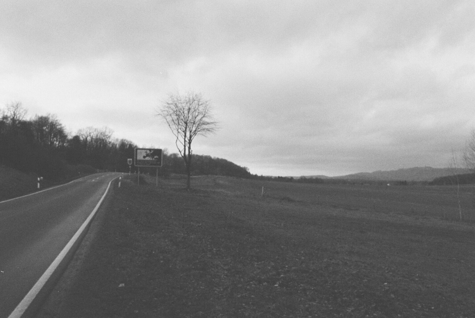 Blick entlang der Landstraße, die die Landkreise Nordhausen und Göttingen verbindet. Am Straßenrand ein Schild, das zeigt, dass Deutschland und Europa an dieser Stelle getrennt waren