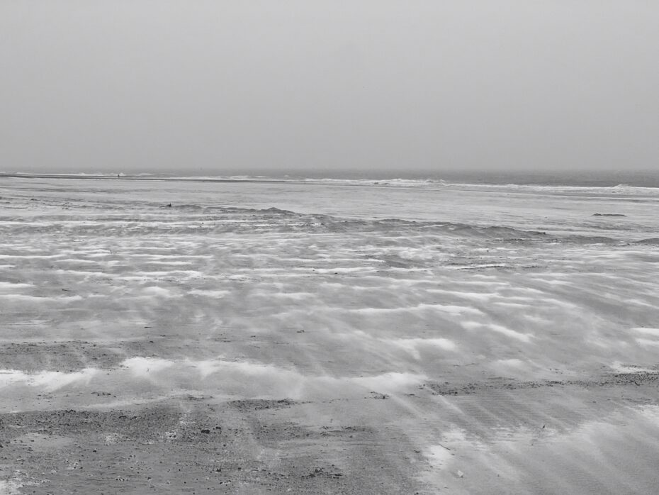 Strandlandschaft, über die kleine Schneemengen hinweggeweht werden