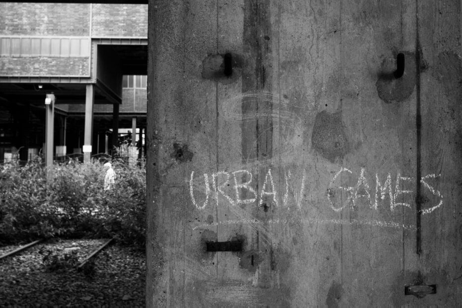 Schwarz-Weiß Bild eines Betonpfeilers mit "URBAN GAMES" Schriftzug aus Kreide