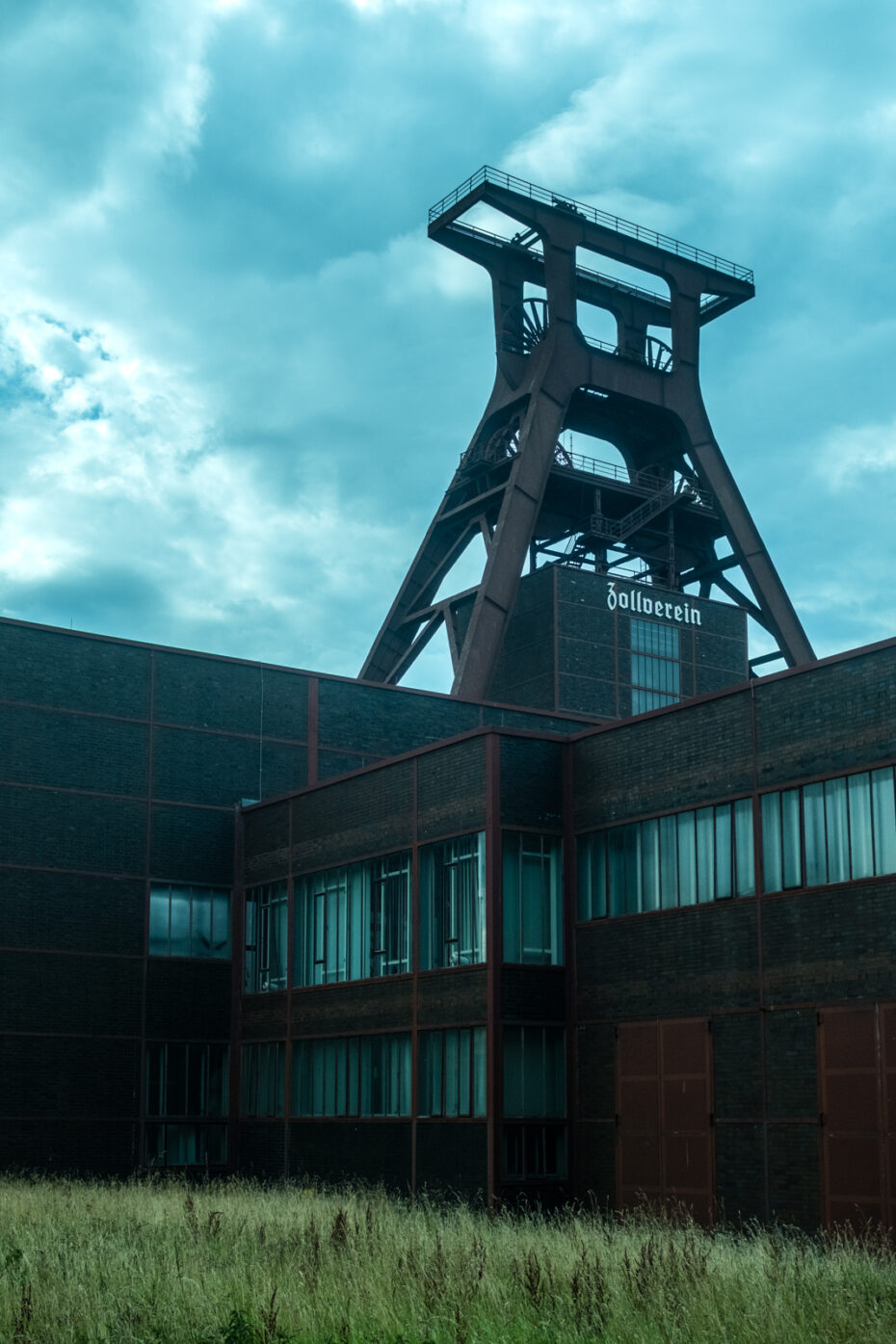 Blick auf den großen Förderturm des Schacht 12, im Vordergrund hohes Gras