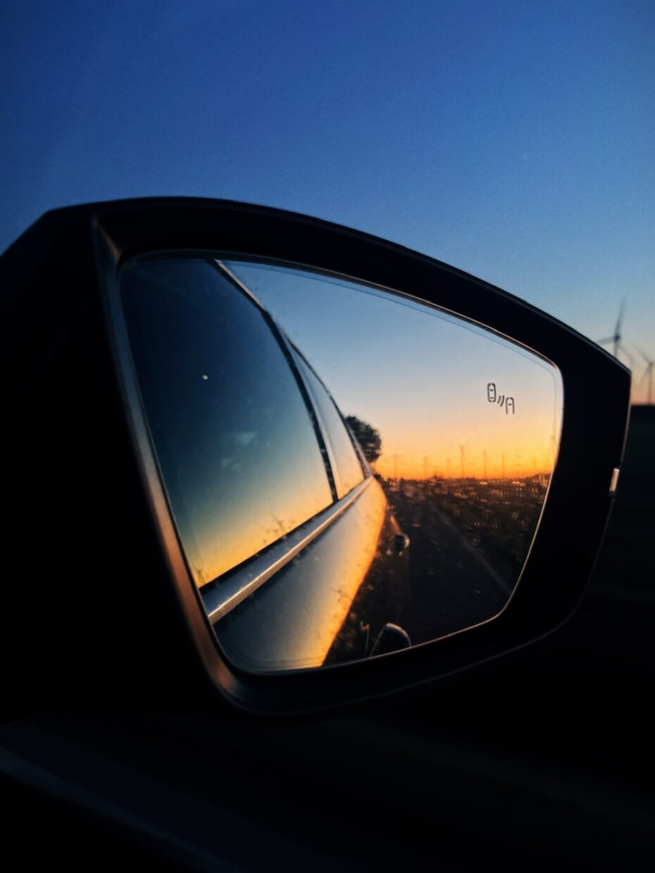 Blick in den Rückspiegel des Autos, in dem sich der Sonnenaufgang spiegelt