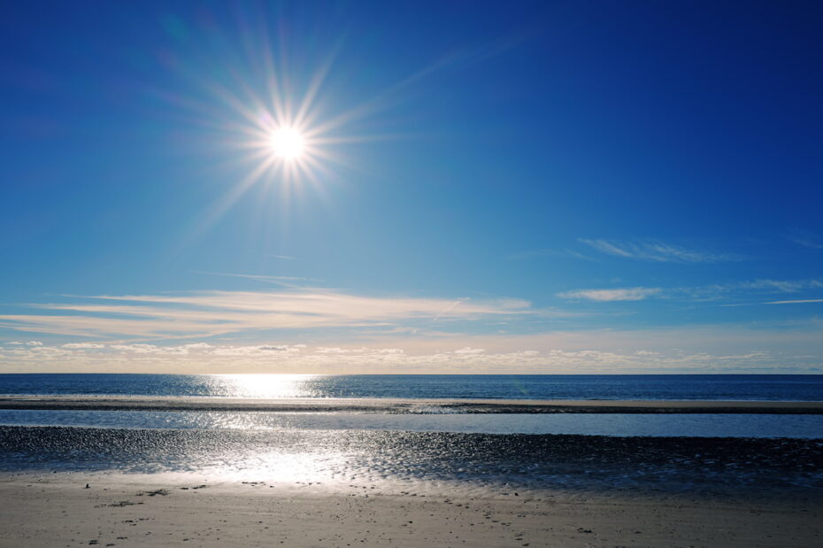 Die Sonne scheint über der Nordsee, der Blendenstern ist deutlich ausgeprägt und das Wasser spiegelt das Licht